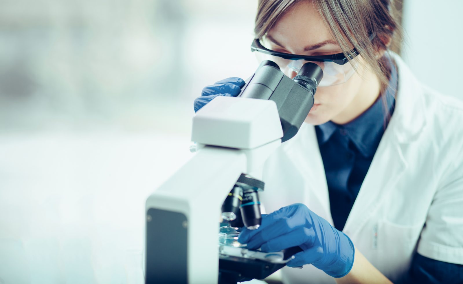 Young scientist looking through a microscope in a laboratory. Young scientist doing some research. Young scientist looking through a microscope in a laboratory. Young scientist doing some research.